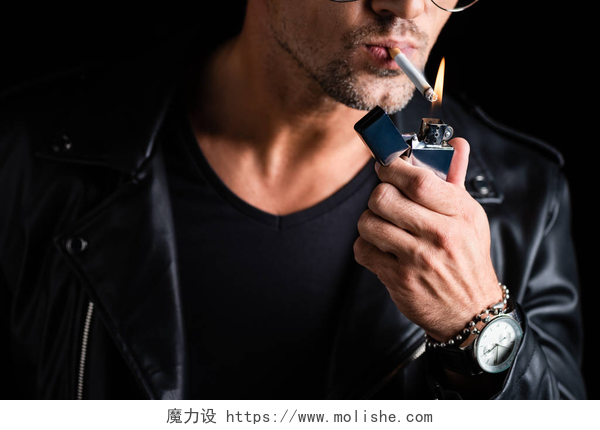 黑色背景中一个男人点燃香烟男人用黑色隔离的打火机点燃香烟的剪影 